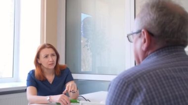 Bir kadın doktor modern bir klinikte hasta bir adamı daha detaylı incelemek için kardiyogram tutuyor. Tıptaki son teknolojiler..