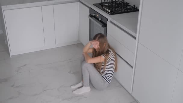 통증으로 고통받는 피곤한 그녀는 방에서 바닥에 앉아있다 — 비디오