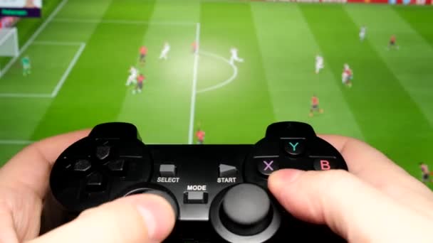 コンソールでサッカーの試合をする 男はジョイスティックを保持し コンピュータゲームをプレイしています — ストック動画