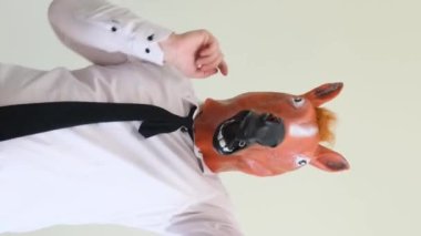 At maskeli bir adam stüdyoda arka planda dans ediyor. Bir adam tarafından yapılan komik bir dans. Ağır çekim. Dikey video