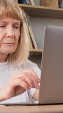 Gözleri iyi görmeyen bir büyükanne dizüstü bilgisayarın başında oturuyor, başı ağrıyor. Bilgisayarın başında vakit geçiren emekli bir kadının yorgun gözleri. Dikey video