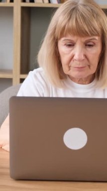 Güzel bir Amerikalı büyükanne dizüstü bilgisayarın başında oturuyor, başı ağrıyor. Bilgisayar başında yorgun bir emekli. Dikey video