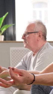 Üst düzey çiftler sağlıklı yaşam tarzına, evde egzersiz ve yoga yapma kavramına bağlılar. Dikey video