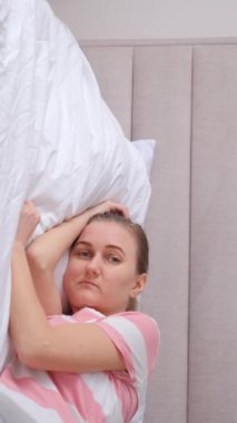 Üzgün kadın yatakta yatıyor, uykusuzluk çekiyor. Dikey video.