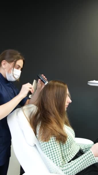 垂直录像 用手电筒和梳子对病人头皮进行检查 在美容院垂直录像 — 图库视频影像
