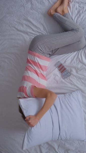 一位中年妇女躺在床上 扭动着肚子痛 由于月经周期而无法入睡 生病或忧郁的女孩在家里睡觉 垂直录像 — 图库视频影像