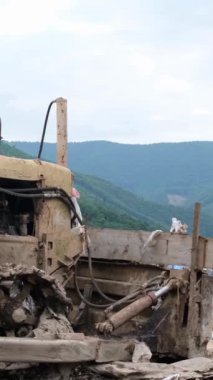 Sıralanmamış çöp yığını, çöplükte bir traktör. Bir sürü plastik çöp, sağlıksız, yeşil ormanın arka planında zehirli atık. Dikey video