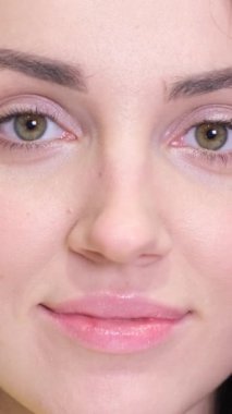 Pozitif ruh hali olan genç bir kadının yüzü. Siyah saçları ve kahverengi gözleri var, çok güzel bir gülümsemesi var. Kapatın. Dikey video