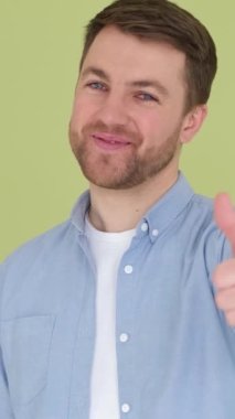 Stüdyo arka planında baş parmak gösteren bir adamın portresi. Güldü ve gözleri neşeyle parladı. Dikey video