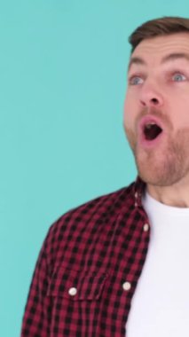 Avrupalı bir adam mavi arka planda duruyor ve vay canına diyor. Gördüklerinden büyülenmiş görünüyor ve yüzü etkileyici bir izlenim veriyor. Dikey video