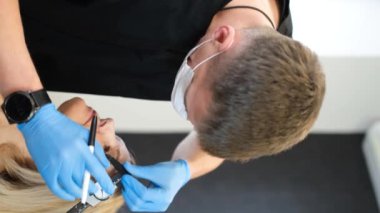 Yüzün üçüncü kısmının cerrahi maskeyle düzeltilmesi. Yüzünde kırışıklıklar, göz kapaklarının kenarları sarkmış. Estetik cerrahın işi. Dikey video