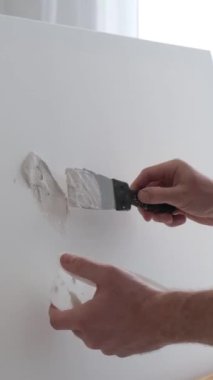 Sanatçı alçı kullanarak beyaz bir tuval üzerinde bir resim yaratıyor. Bir sanatçının soyut bir resim yapma süreci. Dikey video