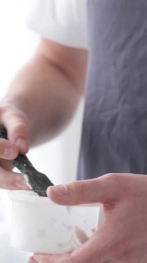 Yetenekli bir erkek sanatçı, fırça kullanarak, beyaz bir tuvalde yağlı boya tablosunun modern bir başyapıtını yaratıyor. Tuval büyük bir stüdyoda bir sehpanın üzerinde. Dikey video