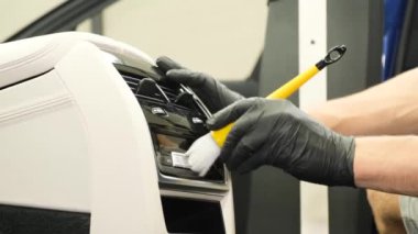 Bir arabanın iç dekorasyonuna yakın çekim. Bir işçi elektrikli süpürgeyle kirli su toplar. Araba kuru temizleme. Dikey video