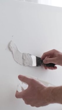 Profesyonel bir sanatçı beyaz bir tuvale metal bir fırça ve sehpa kullanarak resim çizer. Bir sanatçının alçı tablosu yaratma süreci. Dikey video