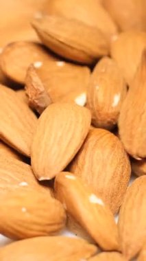 Taze koparılmış bademlerin kaseye yavaşça düştüğü makro bir video. Kase ince bir cildi olan açık kahverengi fındıkla dolu. Dikey video