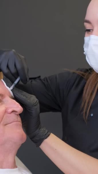 顔の老化に対する注射 皮膚科医は 古い年齢で顔にしわのための注射をする プロの美容師さん バーティカルビデオ — ストック動画