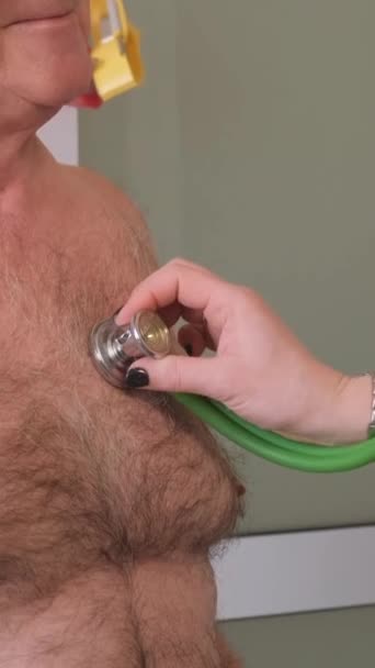 一位女心脏病医生在做体格检查时 用听诊器倾听一位老年男子的心跳 老年人护理 垂直录像 — 图库视频影像