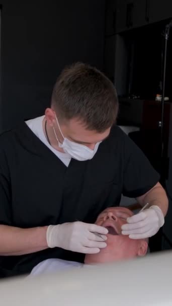 歯科医は高齢者と仕事をし 現代の歯科インプラントを取り付けています 老後の歯科治療について バーティカルビデオ — ストック動画