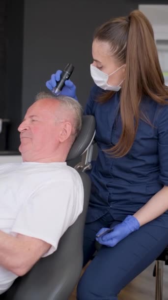 一位三位一体的医生进行头发诊断和老年男子的检查 头发治疗的概念 垂直录像 — 图库视频影像