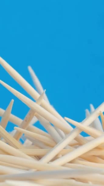 蓝色背景上的一堆旋转的木制牙签 用于牙科卫生的天然木制工具 垂直录像 — 图库视频影像
