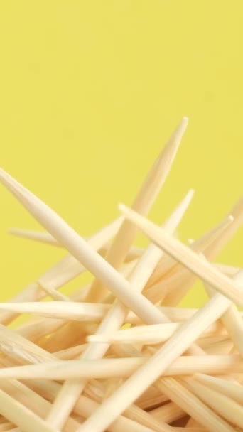 一组在黄色背景上旋转的木制牙签 天然木棍 用于口腔和其他目的 垂直录像 — 图库视频影像
