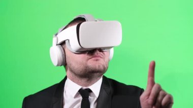 Stüdyoda yeşil arka planda sanal gerçeklik gözlüğü kullanan beyaz iş adamı. Dikey video