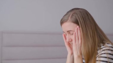 Kafası aşağıda ve elleri yüzünün önünde sıkıca bağlanmış bir kadın. Umutsuzluk, depresyon, migren veya baş ağrısı bakışı.