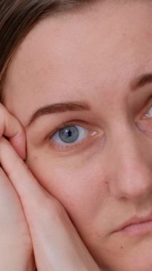 Üzgün, dalgın genç bir kadının yakın plan fotoğrafları, yalnız başına oturan, ilişkileri düşünen, kişisel sorunları olan. Bir kadın evde kendini yalnız, depresyonda hisseder, düşünür ya da özler. Dikey video