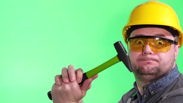 Странный Работник Молотком Руках Желтым Шлемом Смеется Над Камерой Зеленом — стоковое видео