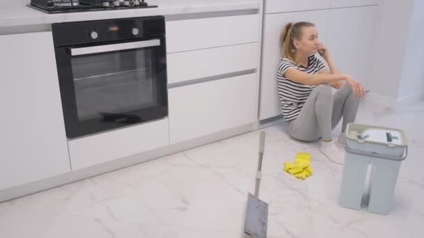 厌倦了的女人一边打扫房子一边打电话 清理房子里的地板 — 图库视频影像
