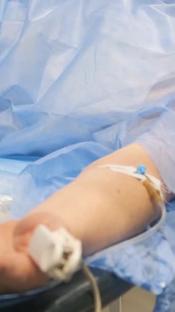 在手术期间 一位白头发的老爷爷躺在手术台上 病人用注射器用管子连接手臂 垂直录像 — 图库视频影像