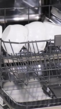 Bulaşık makinesinden bulaşıkları boşaltıyorum. Otomatik bulaşık makinesinde yıkanmış, parlak bulaşıklar. Dikey video
