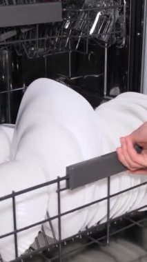Bulaşık makinesinden bulaşıkları boşaltıyorum. Bir ev hanımı otomatik bulaşık makinesinden temiz bulaşıkları alır. Dikey video