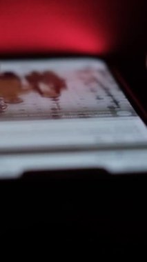 Erkek el, karanlık ışıkta parmaklarıyla akıllı telefon ekranında çalışır. İnternetten bilgi aranıyor. Akıllı telefondan video izliyorum. Dikey video