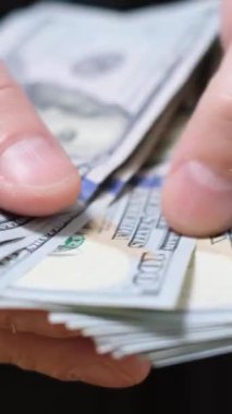 100 dolarlık banknotları nakit sayan bir iş adamının yakın çekimi. İş ve finans kavramı. Dikey video