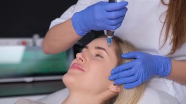 Profesyonel kozmetik uzmanı bir kozmetoloji kliniğinde dermaPen prosedürü uyguluyor. Yüz bakımı yenileniyor. Dikey video