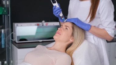 Güzeller güzeli genç bir kadın güzellik salonundaki yüz için mikro cilt ameliyatı oluyor. Dikey video