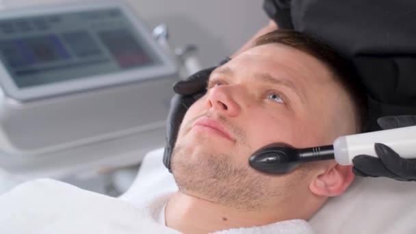 顔の皮膚クレンジング手順 顔のための超音波デバイスの手順 男性のアクネの治療 男性はスパで電動リフトマッサージを受ける バーティカルビデオ — ストック動画