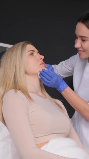 美容師は美しい女の子の唇に注射する 脂肪増殖手順について バーティカルビデオ — ストック動画