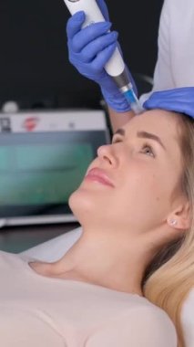 Güzeller güzeli genç bir kadın güzellik salonundaki yüz için mikro cilt ameliyatı oluyor. Dikey video