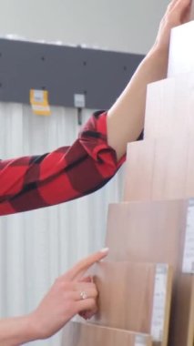 Laminate satış müdürü kaliteli ürün gösteriyor. Tadilat yapılan bir evin zeminini seçmek. Dikey video
