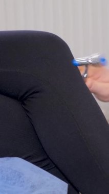 Nörolog hastayı muayene eder, dizine çekiçle vurur, yakın plan. Doktor hastanın sinirsel durumunu kontrol eder. Dikey video
