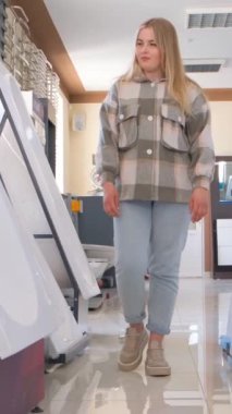 Bir kadın, tesisat dükkanında yeni bir küvet seçiyor. Alışveriş, tamir ve onarım konsepti. Tesisat dükkanı. Dikey video