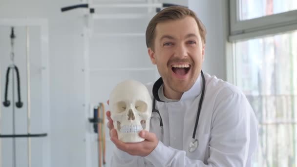 Egy Fiatal Orvos Egy Anatómiai Emberi Koponya Modelljét Tartja Irodában — Stock videók