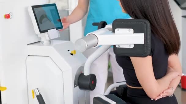 一个年轻的女孩在现代医疗技术机器上做运动 检查病人的脊椎专家的工作 预防脊柱疾病 垂直录像 — 图库视频影像