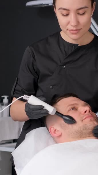 面部皮肤清洁程序 用于面部超声波装置的程序 治疗男性痤疮 一个男人在温泉里接受电动举重按摩 垂直录像 — 图库视频影像