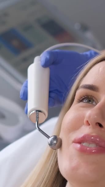 在微电流疗法中 年轻女性面部的特写 一个漂亮的女人在温泉诊所接受了一个刺激性的电 垂直录像 — 图库视频影像