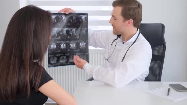 一位脊椎专家向医院的一位病人展示了脊柱的X光图像 年轻女子在脊柱诊所做脊柱检查 垂直录像 — 图库视频影像