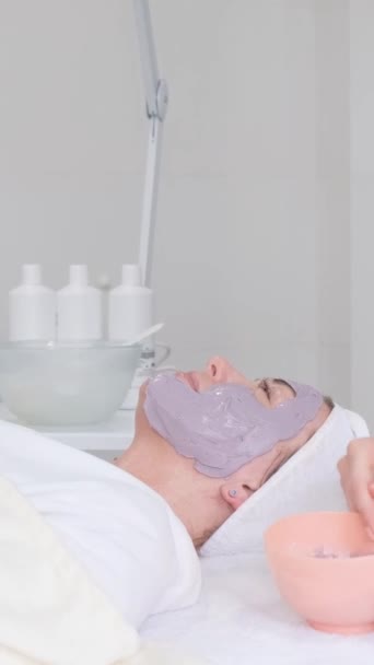 Uma Mulher Relaxa Com Uma Máscara Argila Esteticista Aplica Uma — Vídeo de Stock